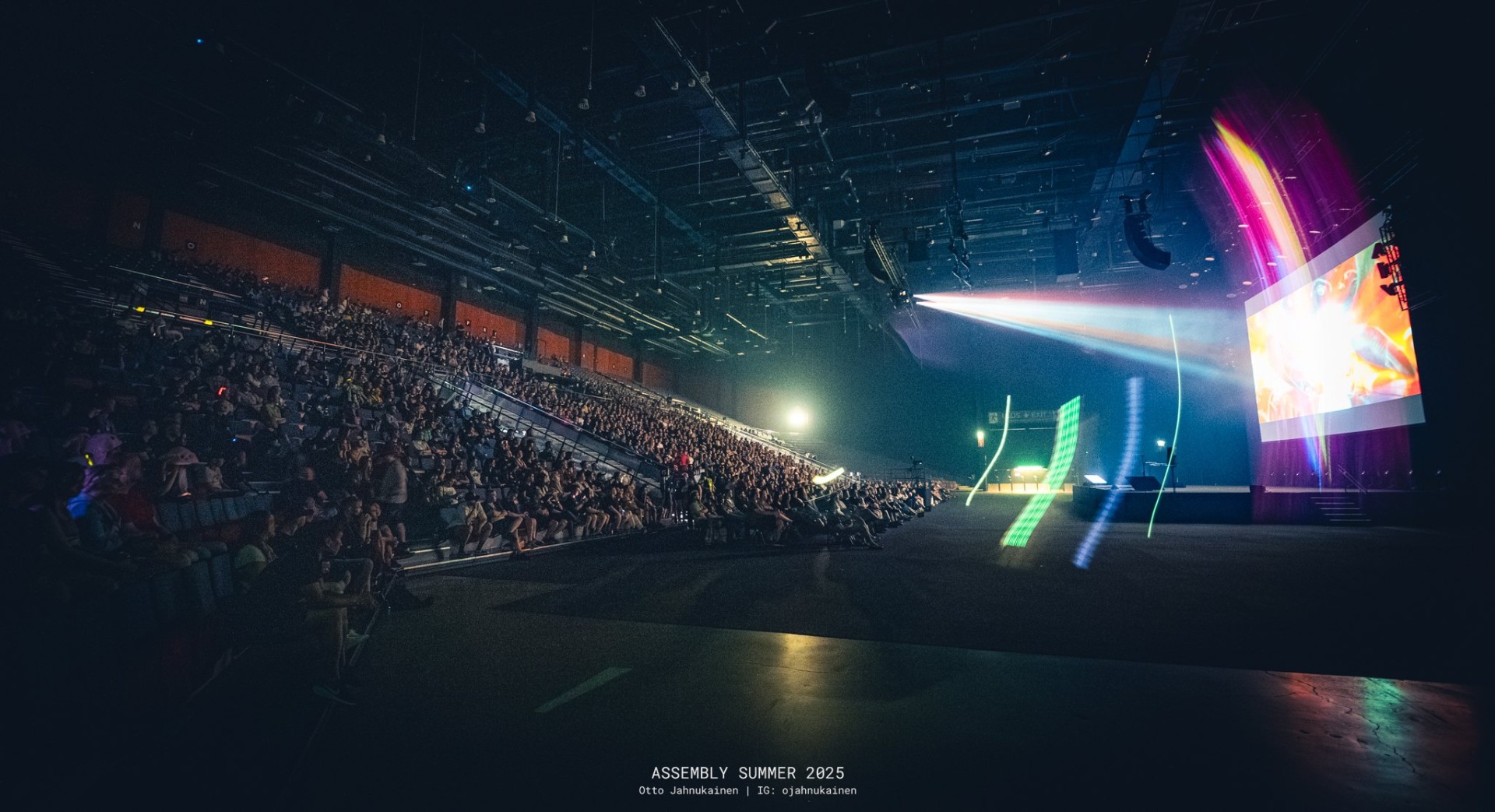 Assembly arena bathed in projector light during a demoscene compo
